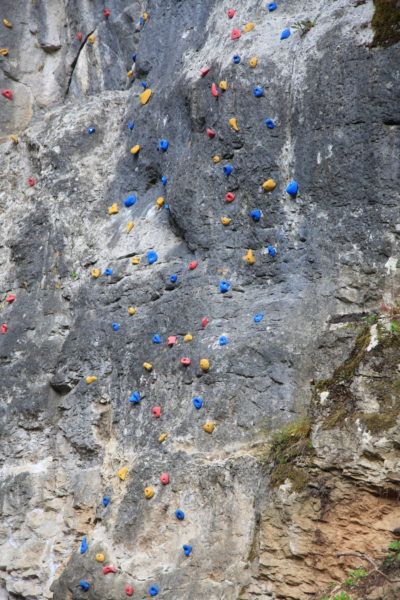 Das Bild zeigt eine Felswand mit künstlichen Klettergriffen aus Plastik